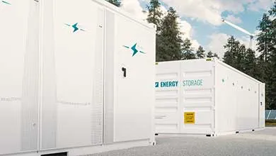 Two large, white energy storage containers outdoors, with evergreen trees and a wind turbine under a partly cloudy sky.