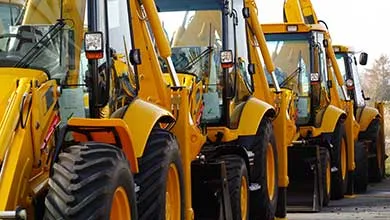 Several yellow backhoe loaders are parked in a straight line.