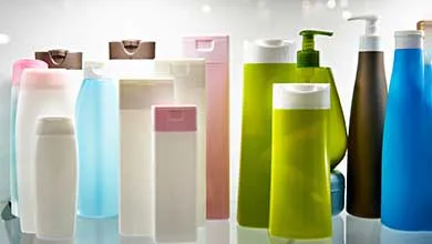 A row of unlabeled plastic bottles in different shapes and colors—white, blue, green, and brown—some with pump dispensers.