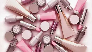 Assortment of cosmetic packaging containers in soft pink and neutral tones arranged on a light background.